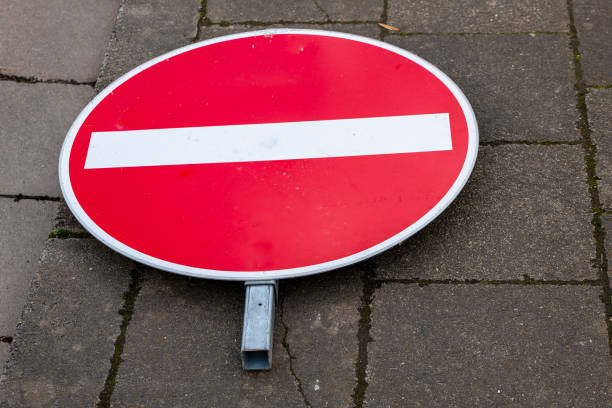 a red road sign lying on the sidewalk no entry