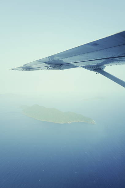 A fixed-wing propeller airplane is about to land at a primitive airport on a tropical island. Surrounding the airport are lush tropical vegetation, with the azure ocean and pristine beaches in the distance. The arrival of this small aircraft heralds the beginning of a relaxed and leisurely vacation journey. Captured with the Leica Q3.