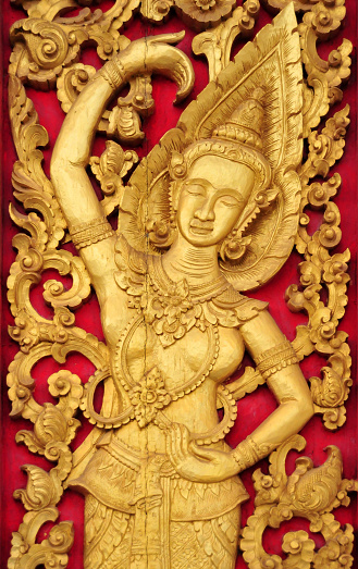 Vientiane, Laos: intricately carved wooden door with golden representation of a mythological figure, an Apsara (female celestial dancer),  in Hinduism, they are regarded to be the celestial demigods who serve as the musicians of the devas, while in Buddhism they are in an intermediate state (between death and rebirth).