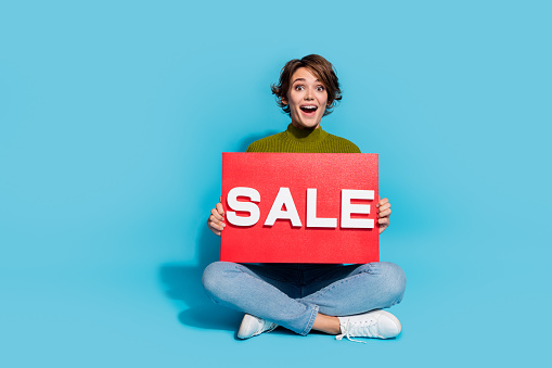 Photo of gorgeous lovely girl wear stylish clothes sitting showing poster black friday sale empty space isolated on cyan color background.
