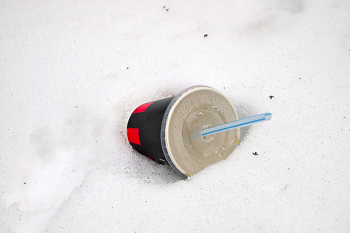 a paper cup with a tube in a snowdrift
