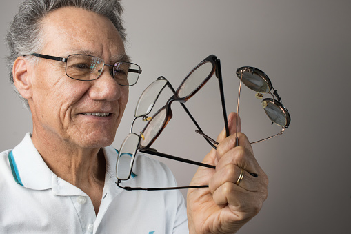 Man checking out and holding up all his old prescription eye glasses