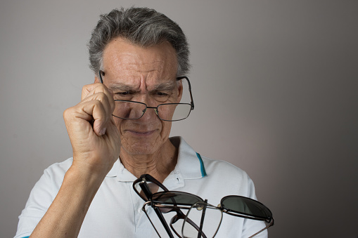 Man checking out and holding up all his old prescription eye glasses