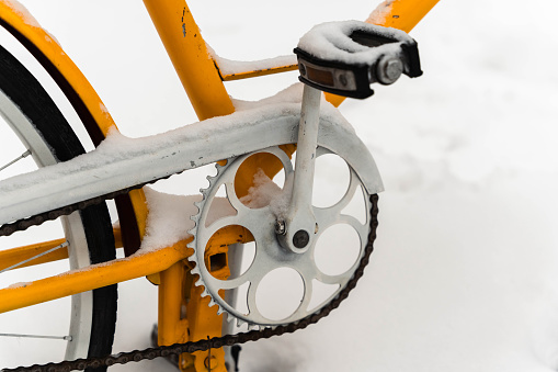 bicycle's chain, gears, and pedals covered in powdery snow during the winter season, creating a serene and picturesque scene of winter's embrace on a classic mode of transport