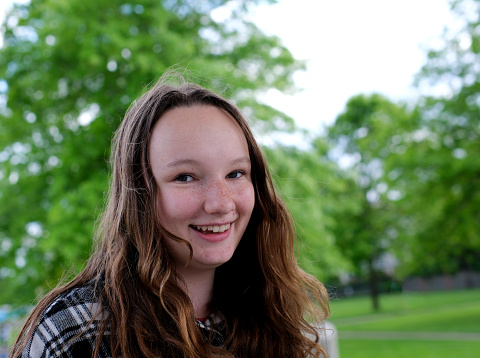 Portrait of a beautiful young woman outdoor smiling. young beautiful girl in a plaid black sweater laughs on the street