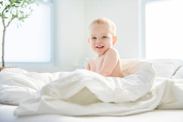 An Adorable baby boy in white sunny bedroom.