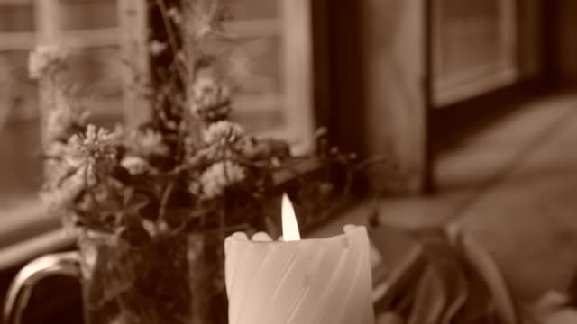 Candlelight in the dark, flowers , umbrella on window sill. Cozy evening at home. vintage toned. Burning candle. Sepia toned