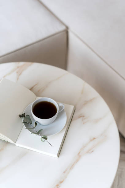 istock Notebook and cup of coffee decorated eucalyptus branch on round marble table 2048145398