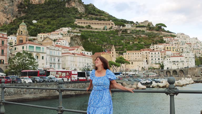 Happy Woman in Blue Dress Walking at Harbour with Scenic View of Amalfi