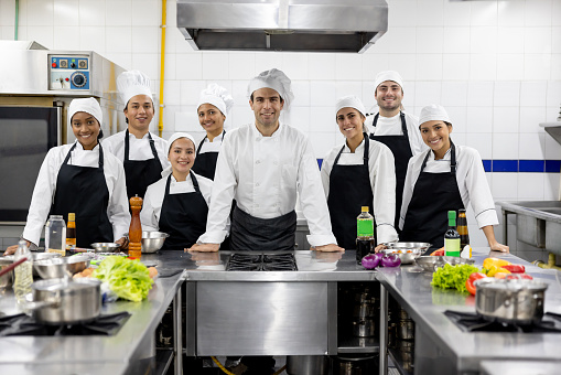 Happy Latin American chef smiling with a group of students in a cooking class and looking at the camera