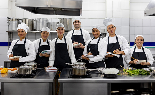 Group of Latin American students smiling in a cooking class and looking at the camera - education concepts