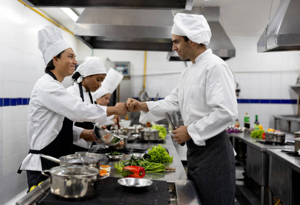 istock Chef congratulating a student in a cooking class giving him a fist bump 2048177036