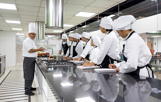 Latin American chef teaching a cooking class to a group of students - education concepts