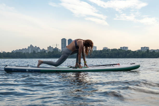 istock Young woman stretches legs balancing on paddleboard 2048211145
