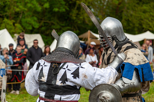 Locronan, France - May 07 2023: Two men in medieval armor fighting during a buhurt demonstration.