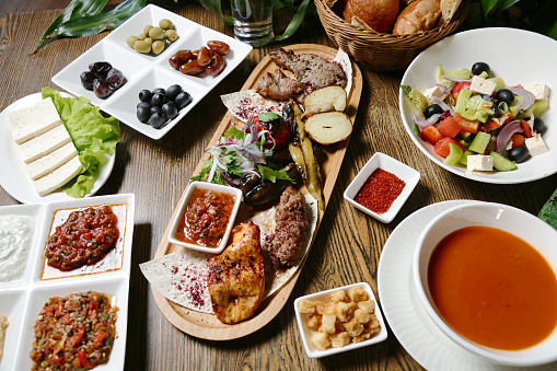 A wooden table is covered with an assortment of delectable dishes and plates loaded with food.