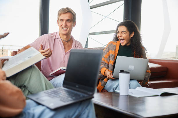 istock Diverse group of college students talking and laughing while studying together at school 2048231778