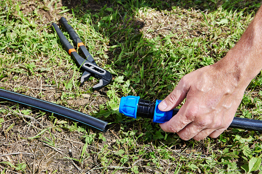 Connecting HDPE pipes with compression fitting coupling when installing irrigation water supply.