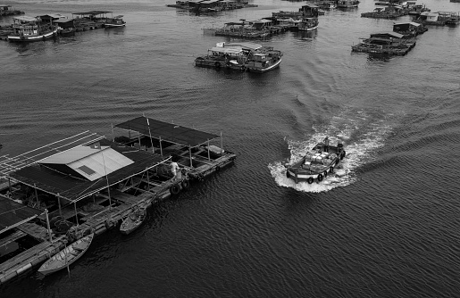 HMAS Supply of the Royal Australian Navy departs Garden Island and prepares to sail out of Sydney Harbour.  She sails past HMAS Adelaide (left) and HMAS Warramunga (right).  She is assisted by two tugboats. The headland jutting out into the harbour is Bradleys Head.  North Head and the harbour entrance are visible at the top left.  This image was taken from Level 29 of Chifley Tower in the afternoon of 6 February 2023.