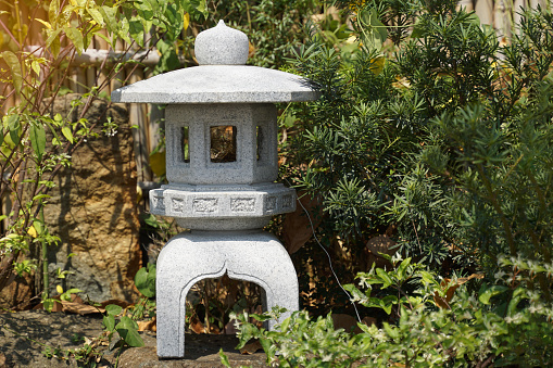 Stone lanterns in a Japanese style rock garden Placed at a distance from each other on the side of the path to see the garden. Soft and selective focus.