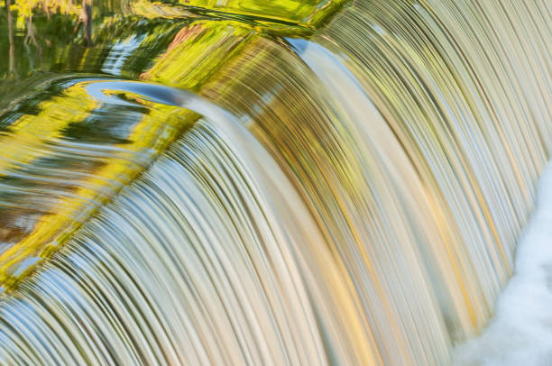 Landscape of the Portage Creek cascade captured with motion blur and with reflections of summer foliage in calm water, Milham Park, Kalamazoo, Michigan, USA