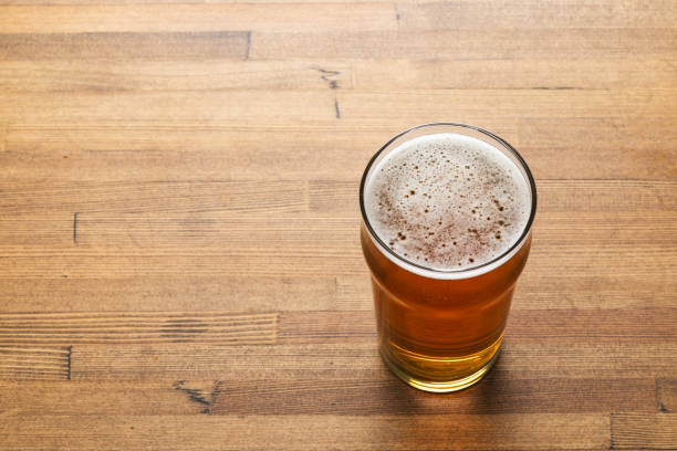 craft beer in pint glass on a wooden table - rustic beer brewery indoors 뉴스 사진 이미지