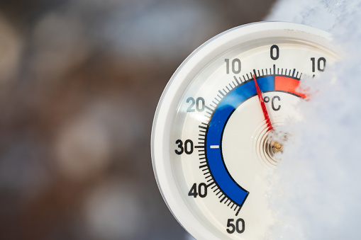 Round thermometer with celsius scale indicating minus 5 degree ambient temperature - winter weather concept