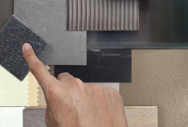 istock interior designer's hand select material samples including corrugated glasses, grainy quartz, stone ceramic tiles, black marble, leather laminated, wooden flooring tiles, drapery in close up view. 2048340026
