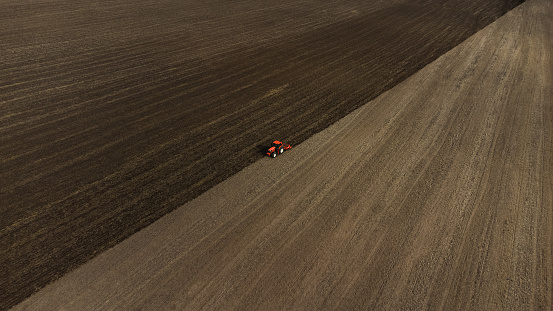 Drone stock photo of a red tractor plowing the field