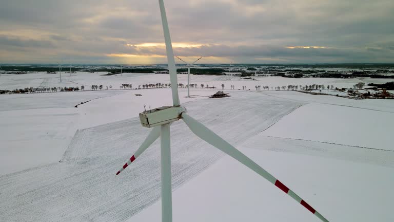 Wind turbines generating renewable electric energy, protect environment and save ecology in agricultural field covered with cold winter snow