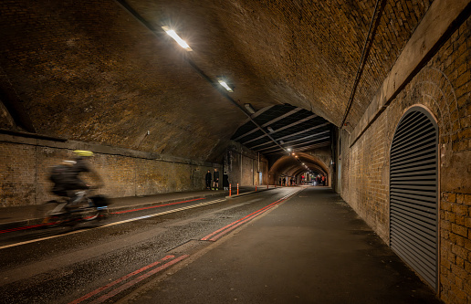 Southwark, London, UK: Bermondsey Street passing through a road tunnel under the London Bridge to Greenwich Railway Viaduct with cyclist and pedestrians.