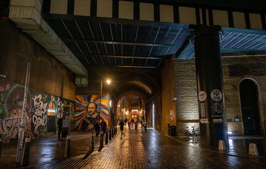 Southwark, London, UK: Clink Street at night. Looking under the railway viaduct towards the Clink Prison Museum in the London borough of Southwark.