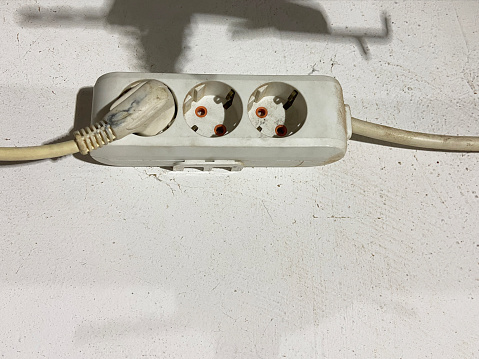 Electric sockets and electric plugs. Electrical outlet with plugs hanging on wall