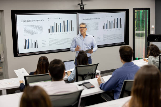 Teacher teaching a class to a group of MBA students Latin American teacher teaching a class to a group of MBA students and using visual aids - education concepts teacher projector stock pictures, royalty-free photos & images