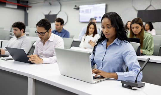 Group of male and female high school students does research in the high school computer lab. The teenage friends enjoy learning and studying together.