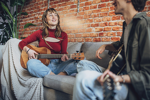 Two people, male and female musicians rehearsing their song in modern studio together.