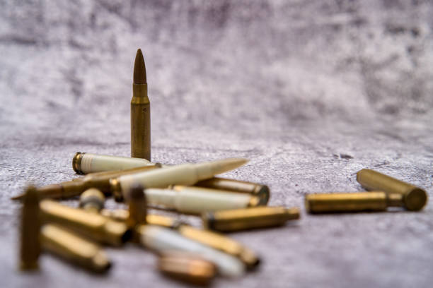 From above of collection of fired golden bullets and unfired cartridges with white plastic case arranged on rough floor at daytime