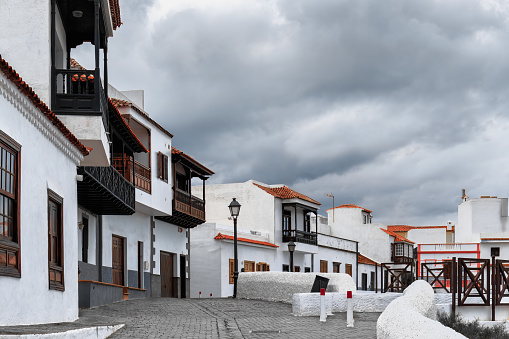 Explore the historic center of Candelaria, Tenerife island, with its cobblestone streets lined with white houses and a dramatic cloudy sky. Spain.