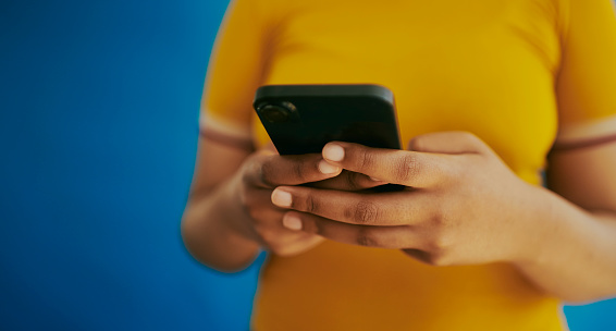 An unrecognisable woman texting and staying connected in the fast-paced digital age. An up-close shot of hands texting on a mobile phone with copy space. Stock photo