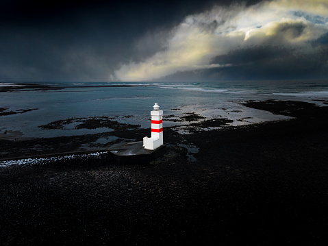 View from above at the Gardur Lighthosue in Iceland with dramatic sky over the Atlantic Ocean and black beach