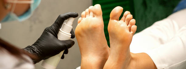 a woman getting a pedicure and pedicurist moisturizing female feet with lotion spraying in a beauty salon. - pedicure human foot podiatrist moisturizer foto e immagini stock