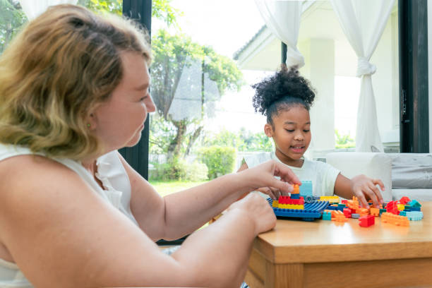 istock Elementary-aged Latin granddaughter playing the plastic building block together with her senior white American grandmother on their leisure time at the cozy living room for spending the quality time with care and strengthening the relationship. 2048490451