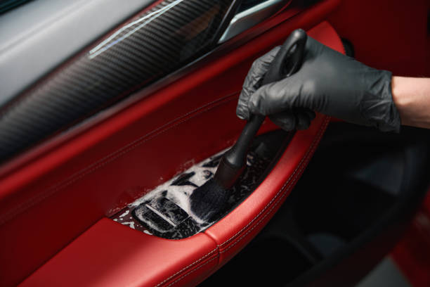 Professional auto detailing professional is cleaning car interior Closeup of male hand in nitrile glove brushing automotive door panel armrest coated with soapy solution car door panels stock pictures, royalty-free photos & images