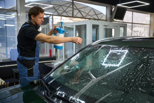 istock Car detailer is applying PPF to outer surface of automobile windscreen 2048572785