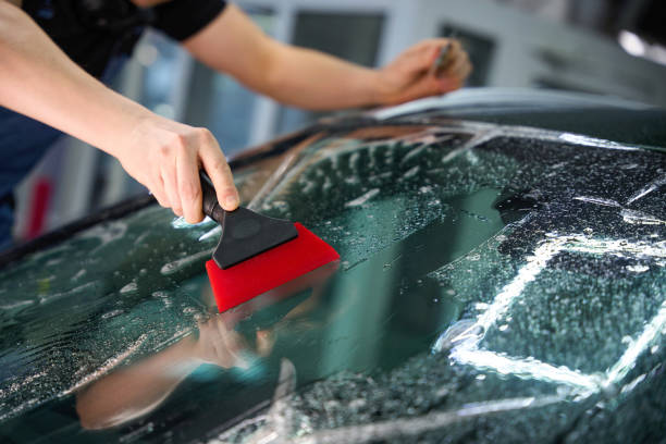 istock Car detailing professional smoothing out protective film on windshield 2048572789