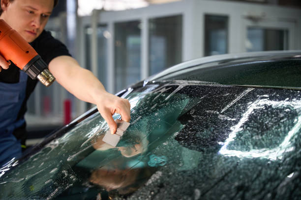 istock Auto detailer removing air bubbles and moisture from PPF on windscreen 2048572791