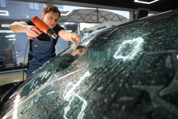 istock Car detailer removing moisture and air bubbles from windshield protective film 2048572795