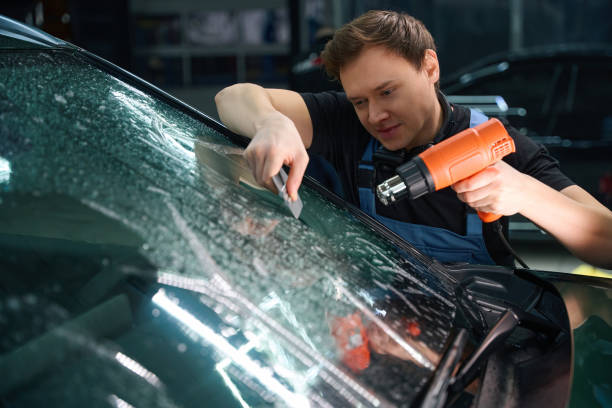 istock Automotive detailing professional is removing air bubbles from windshield PPF 2048572800