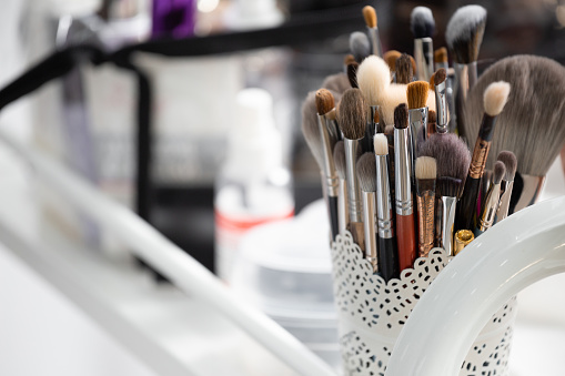 A set of professional brushes and applicators for makeup of various sizes and shapes in an organizer on the makeup artist's desktop. Beauty tools. Brushes in a glass.