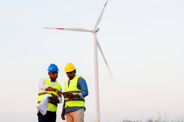 istock Two young Engineers wearing uniform ,helmet hold document inspection work in wind turbine farms rotation to generate electricity energy 2048633221